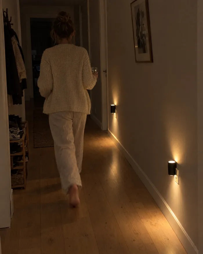 Kvinne på vei gjennom en mørk gang der vegglampene lyser ved gulvet