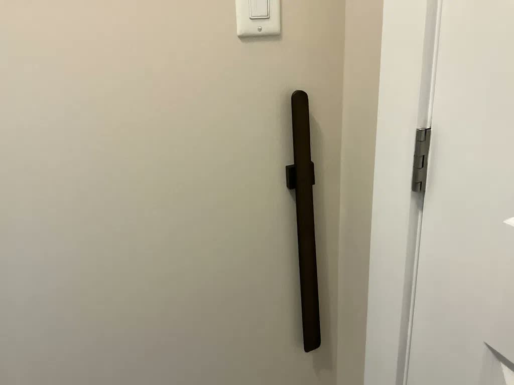Nesten svart skohorn på beige vegg ved siden av hvit dør, med lysbryter over