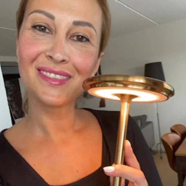 Kunde holder Copenhagen bordlampe i gull opp foran seg